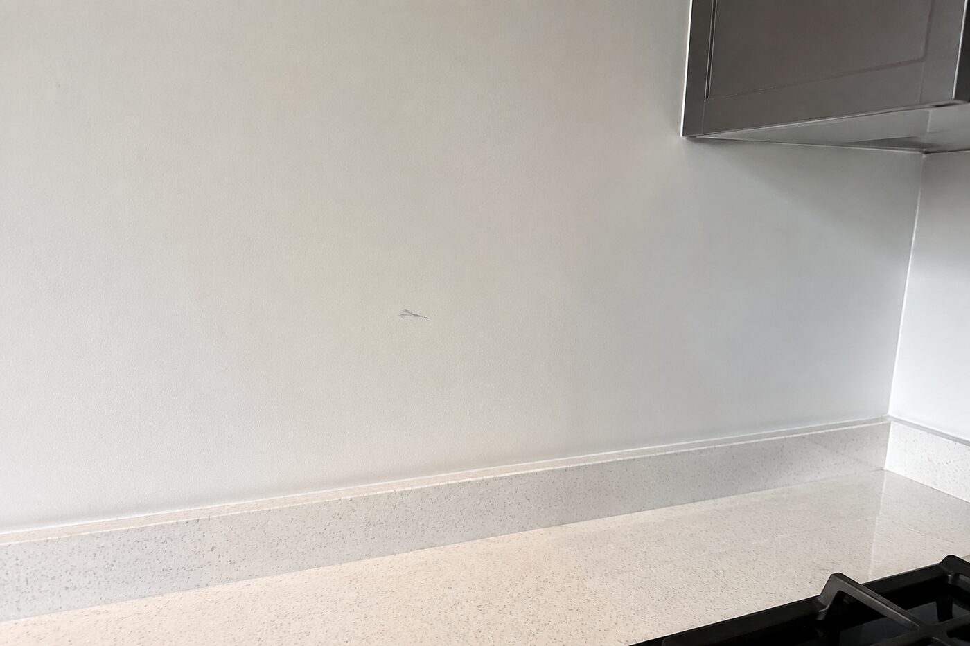 Kitchen wall above a light worktop, with a small scuff on the paint finish.
